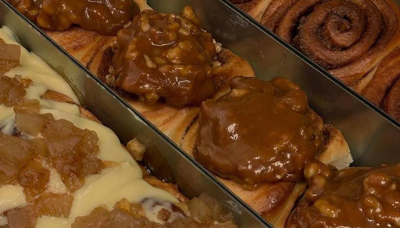 Glossy cinnamon buns in long metal tins