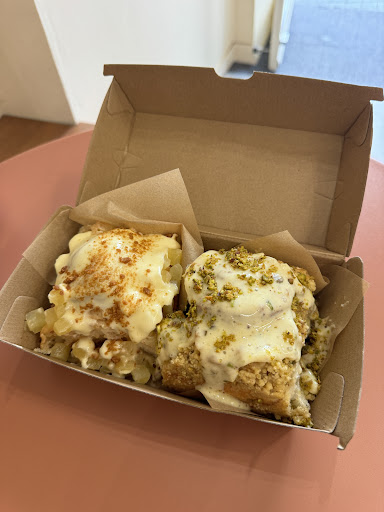 Two frosted cinnamon buns in a takeaway box